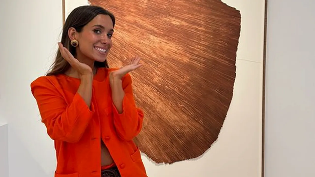 María Pombo en una galería de arte con traje naranja vibrante.